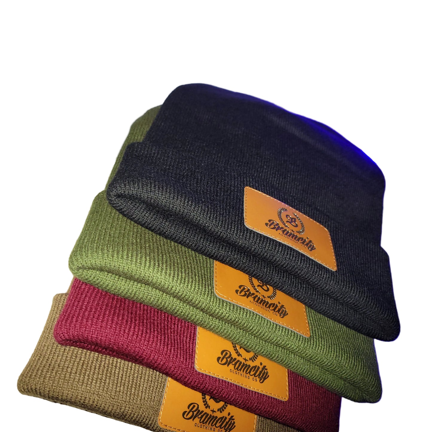 Four beanies in black, green, red, and brown with a brand logo on a textured surface.